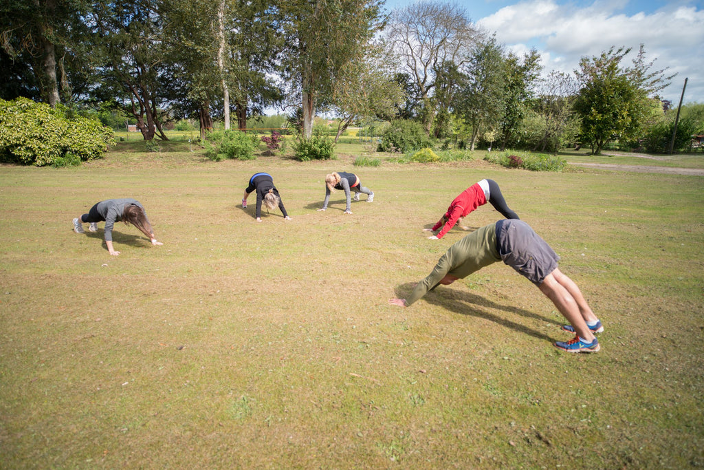 Small group doing outdoor yoga on grass during a Yoga & Trek session